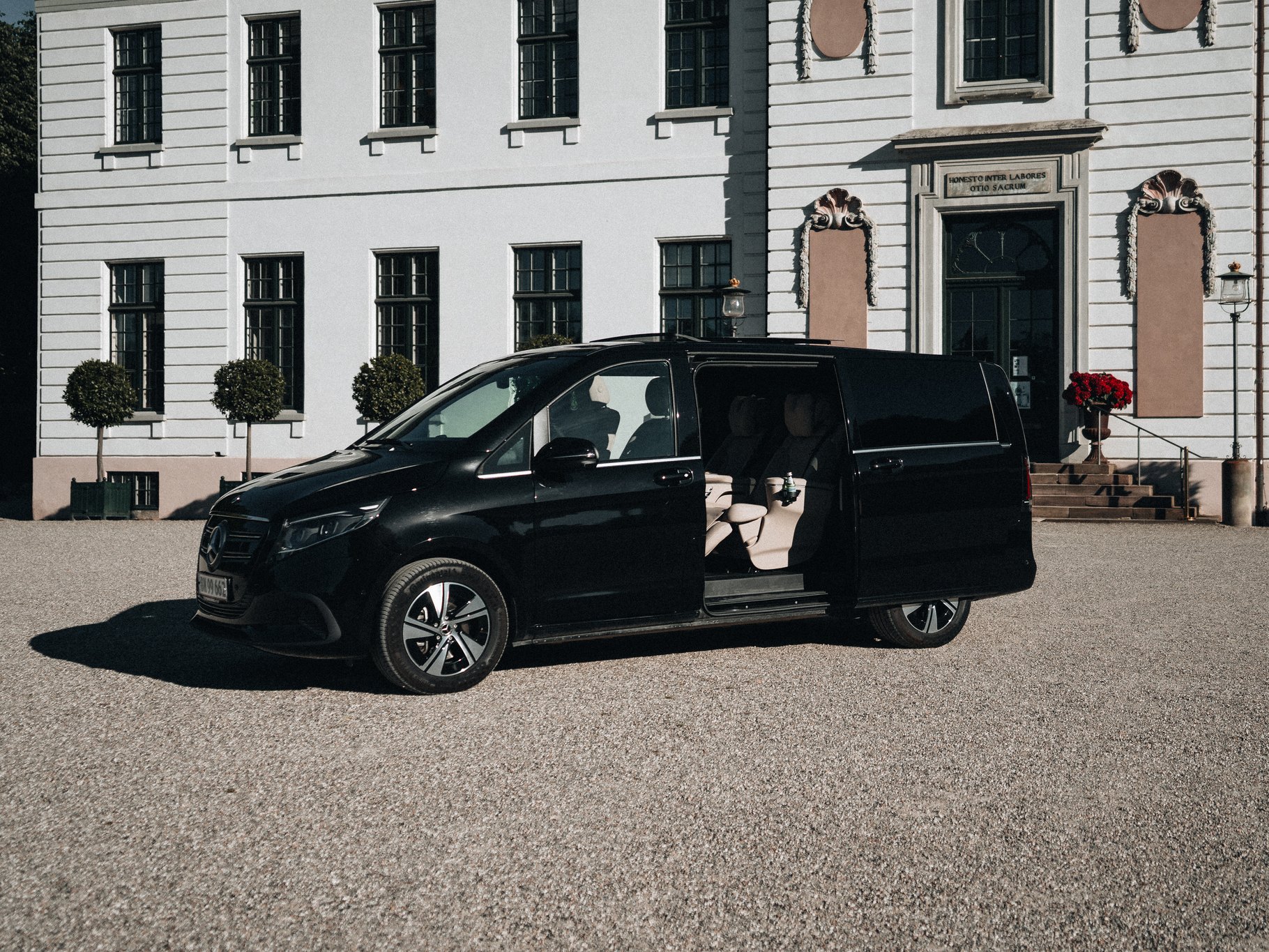 Mercedes-Benz EQV VIP, the LuxLimo Executive Lounge, with its doors open in front of a Danish manor house