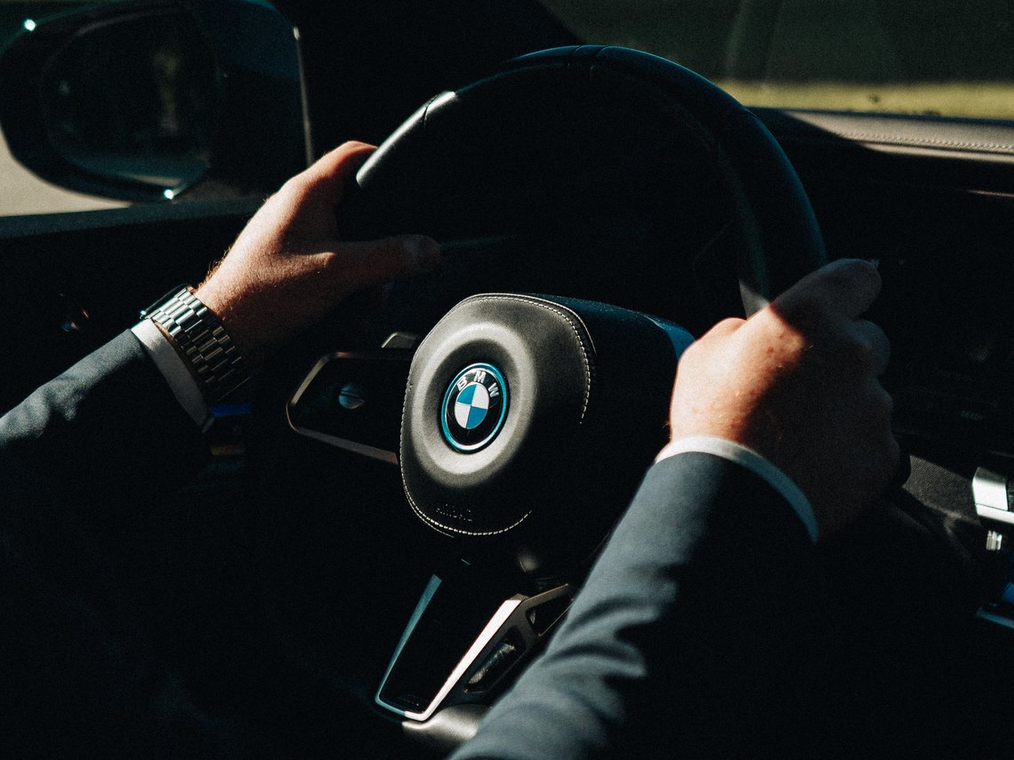 LuxLimo chauffeur's hands on the steering wheel of the BMW i7, Lux